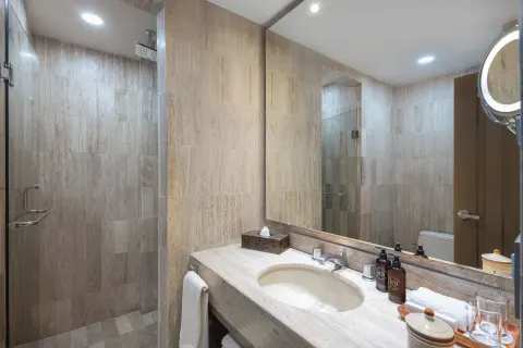 Deluxe Studio bathroom with vanity, mirror and glass shower at Velas Vallarta Suites Resort.