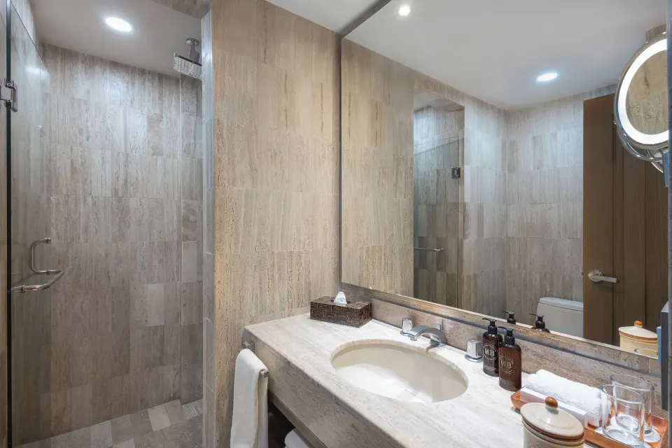Deluxe Studio bathroom with vanity, mirror and glass shower at Velas Vallarta Suites Resort.