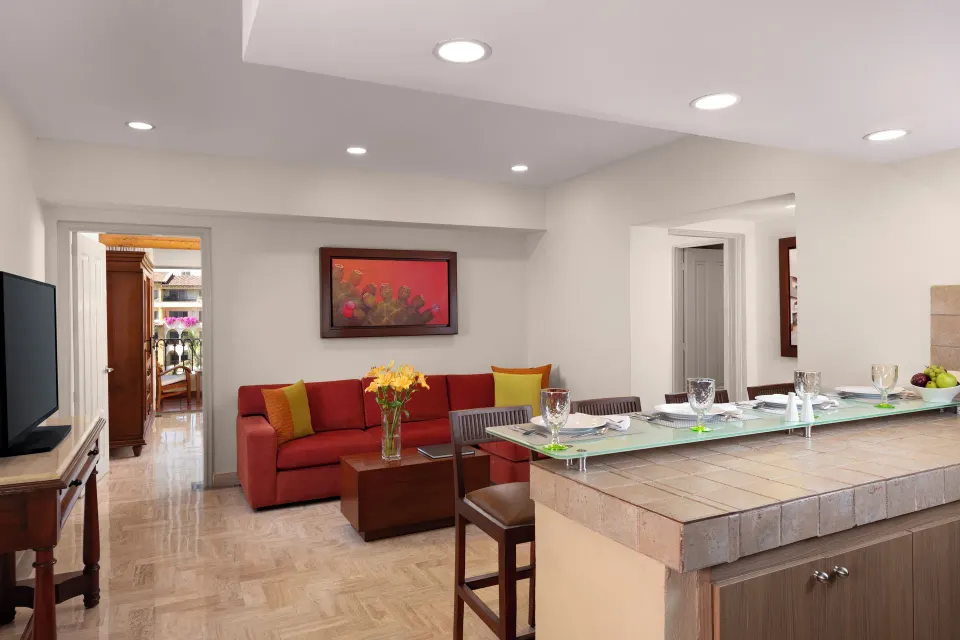 Family Suite living and dining area at Velas Vallarta Suites Resort with red sofa and breakfast bar.