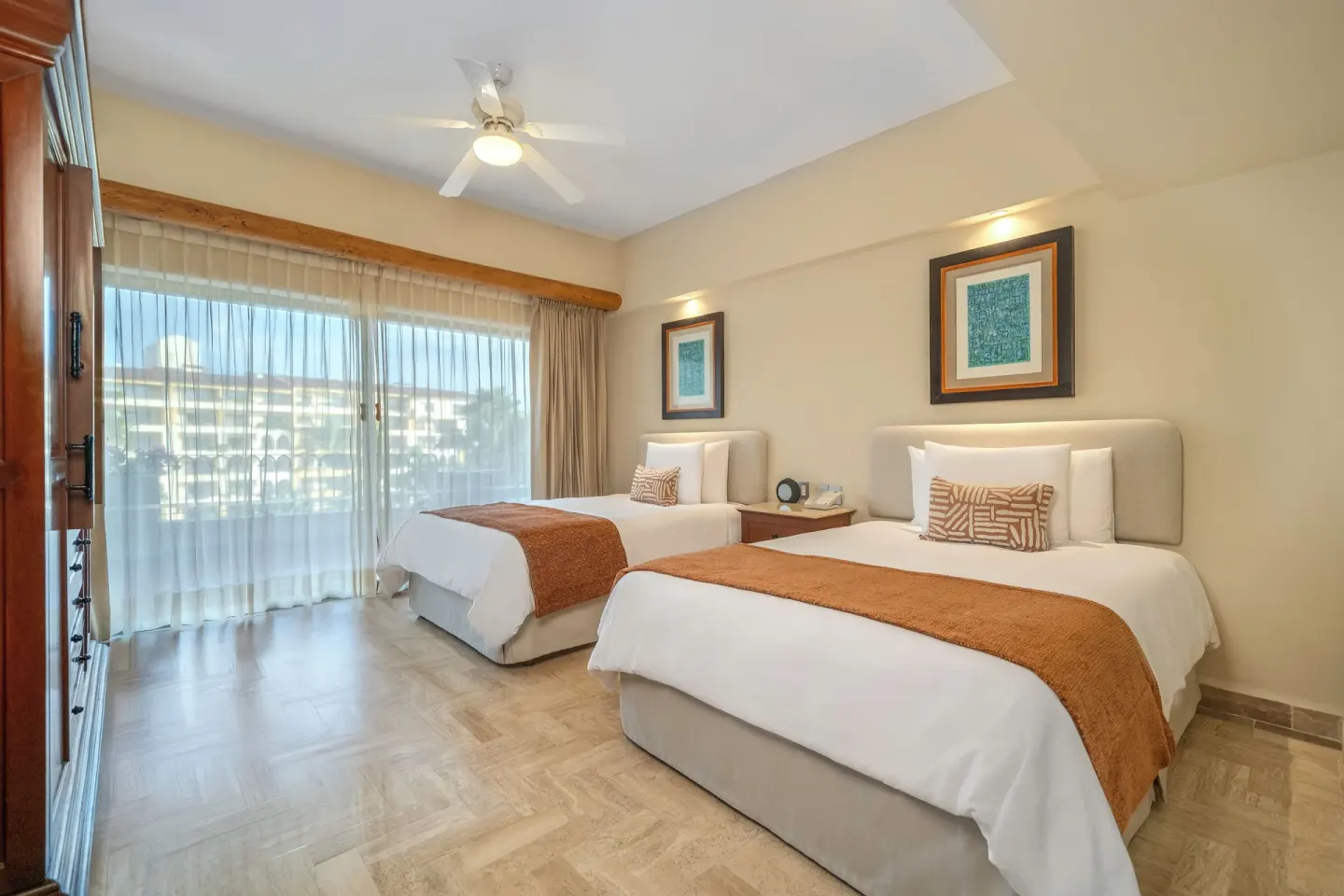 Family Suite bedroom at Velas Vallarta Suites Resort with two beds and sliding glass doors.