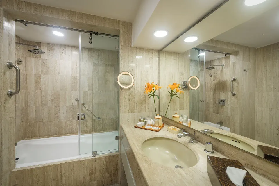 Suite bathroom with tub, glass shower screen, and vanity at Velas Vallarta Suites Resort.