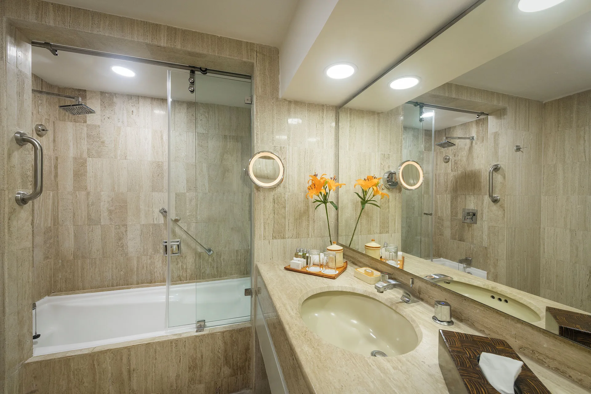 Suite bathroom with tub, glass shower screen, and vanity at Velas Vallarta Suites Resort.