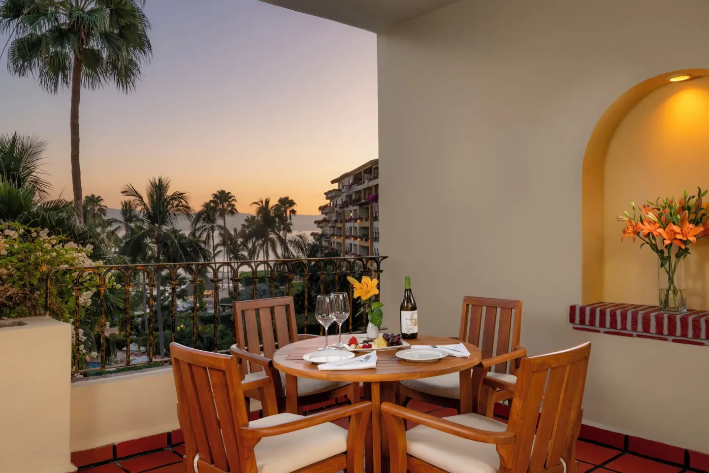 One Bedroom Suite balcony dining setup with palm and ocean views at Velas Vallarta Suites Resort.
