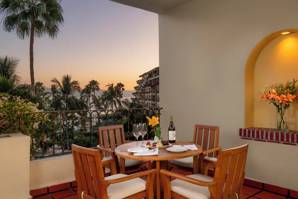 One Bedroom Suite balcony dining setup with palm and ocean views at Velas Vallarta Suites Resort.