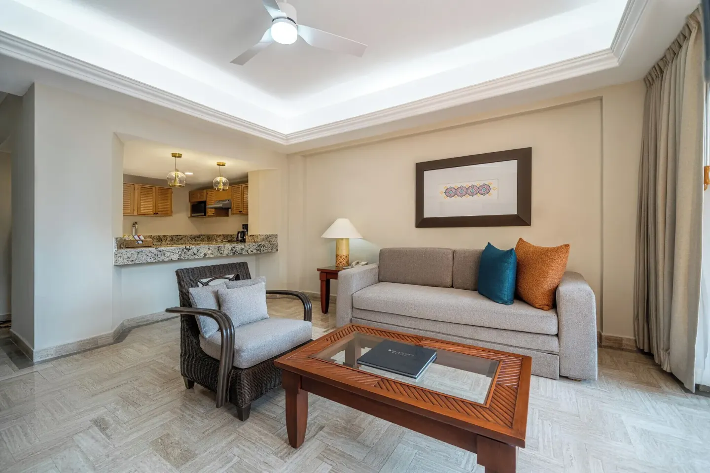 One Bedroom Suite living area with sofa and kitchenette at Velas Vallarta Suites Resort.