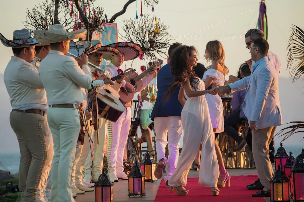 Guests dance beside a mariachi band during a seaside event at Velas Vallarta Suites Resort.