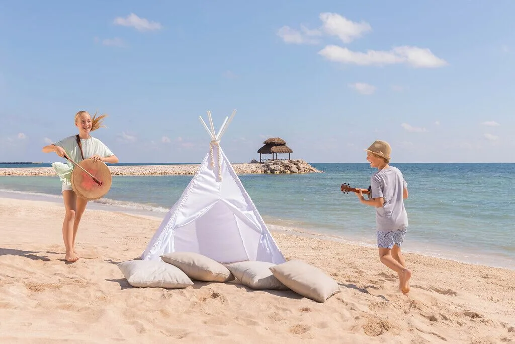 Children play music beside a beach teepee at Ventus at Marina El Cid Spa & Beach Resort.