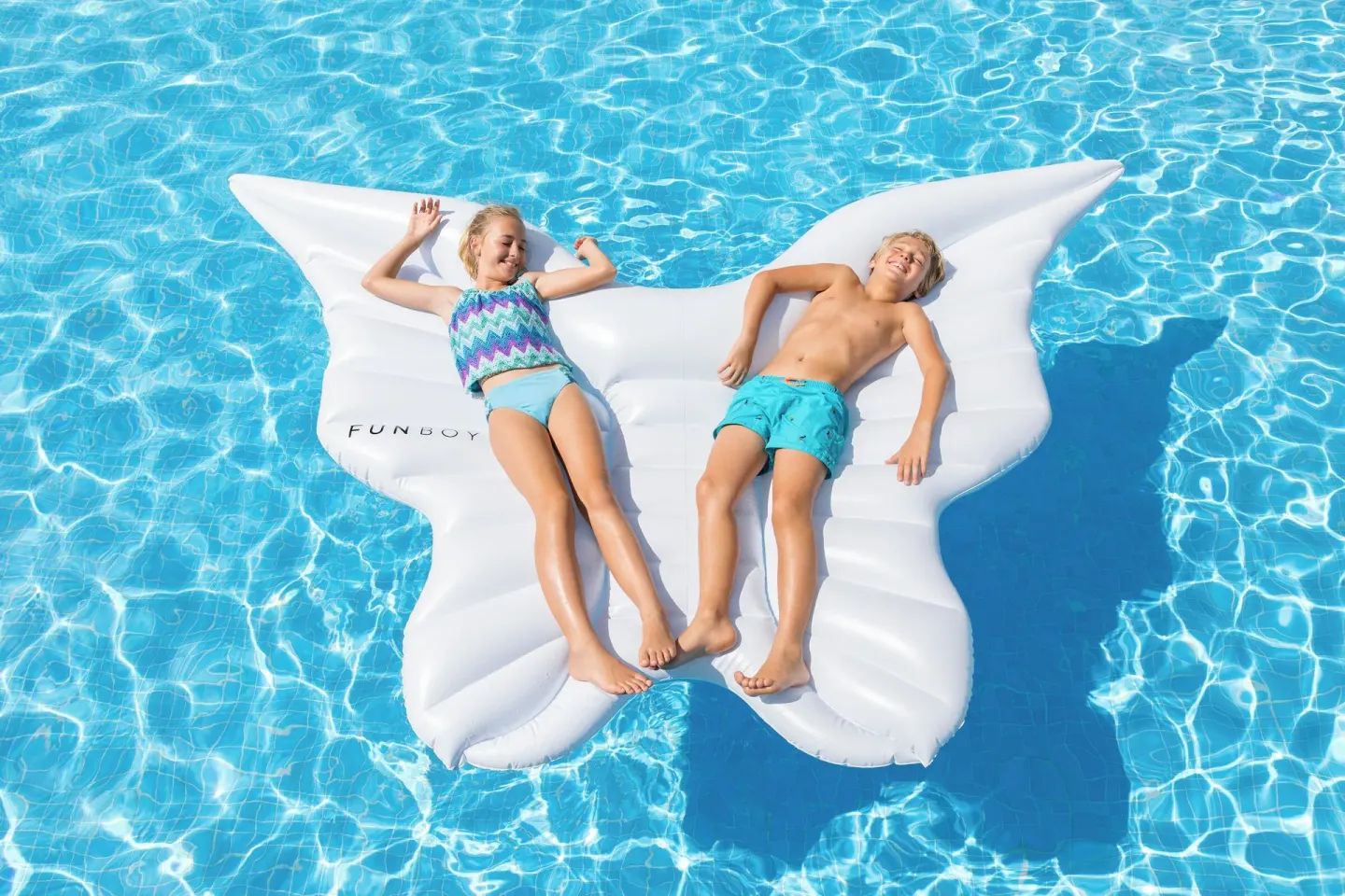 Two children relax on a butterfly-shaped pool float at Ventus at Marina El Cid Spa & Beach Resort.