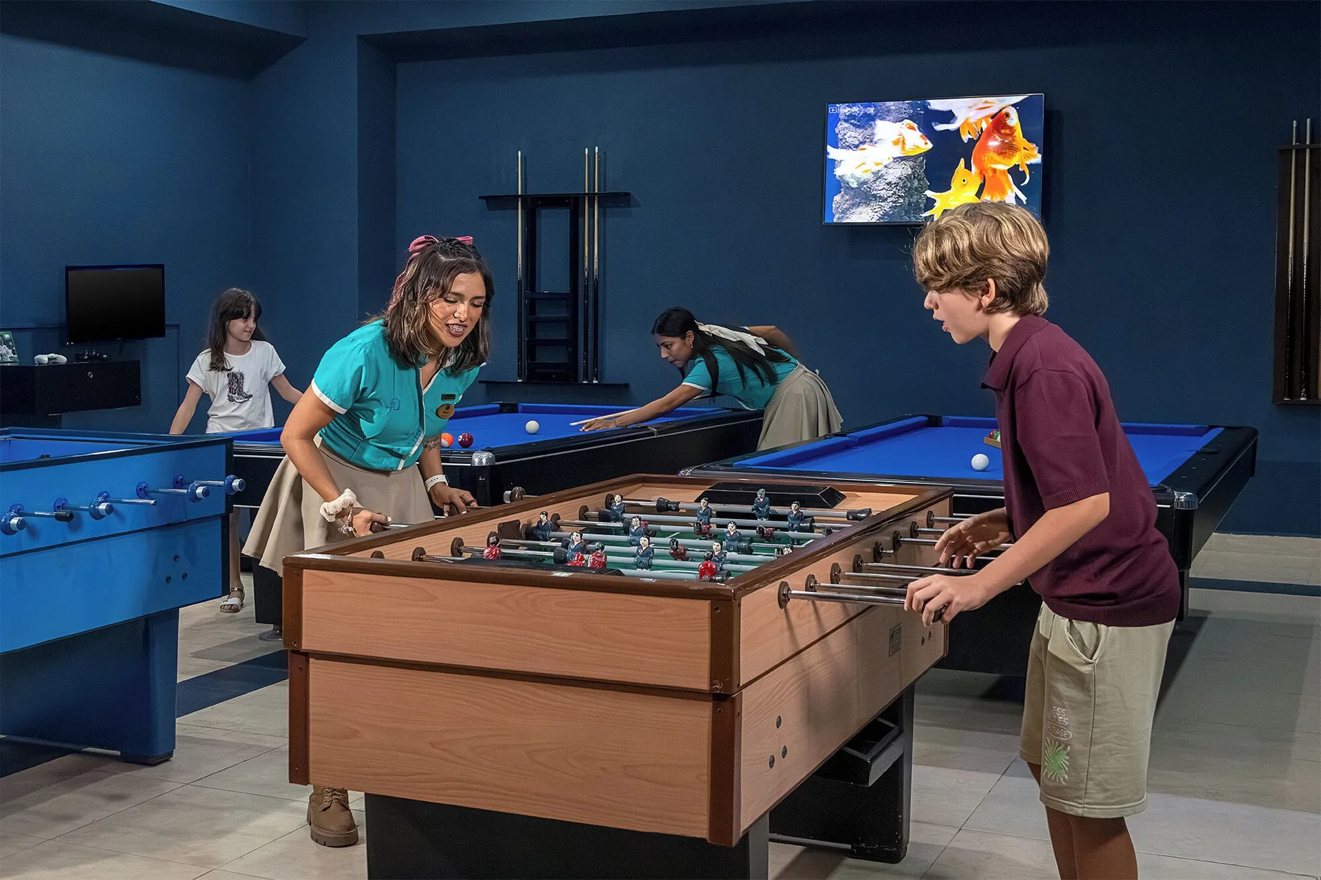 Kids play foosball and pool in the game room at Ventus at Marina El Cid Spa & Beach Resort.