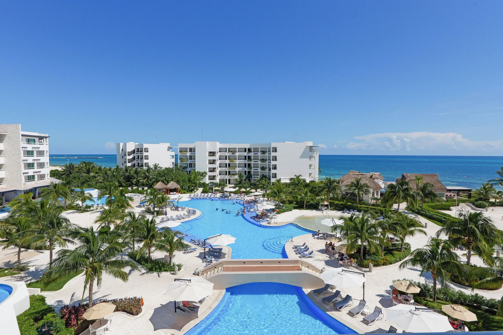 Aerial view of pools, palms, guest buildings, and ocean at Ventus at Marina El Cid Spa & Beach Resort.