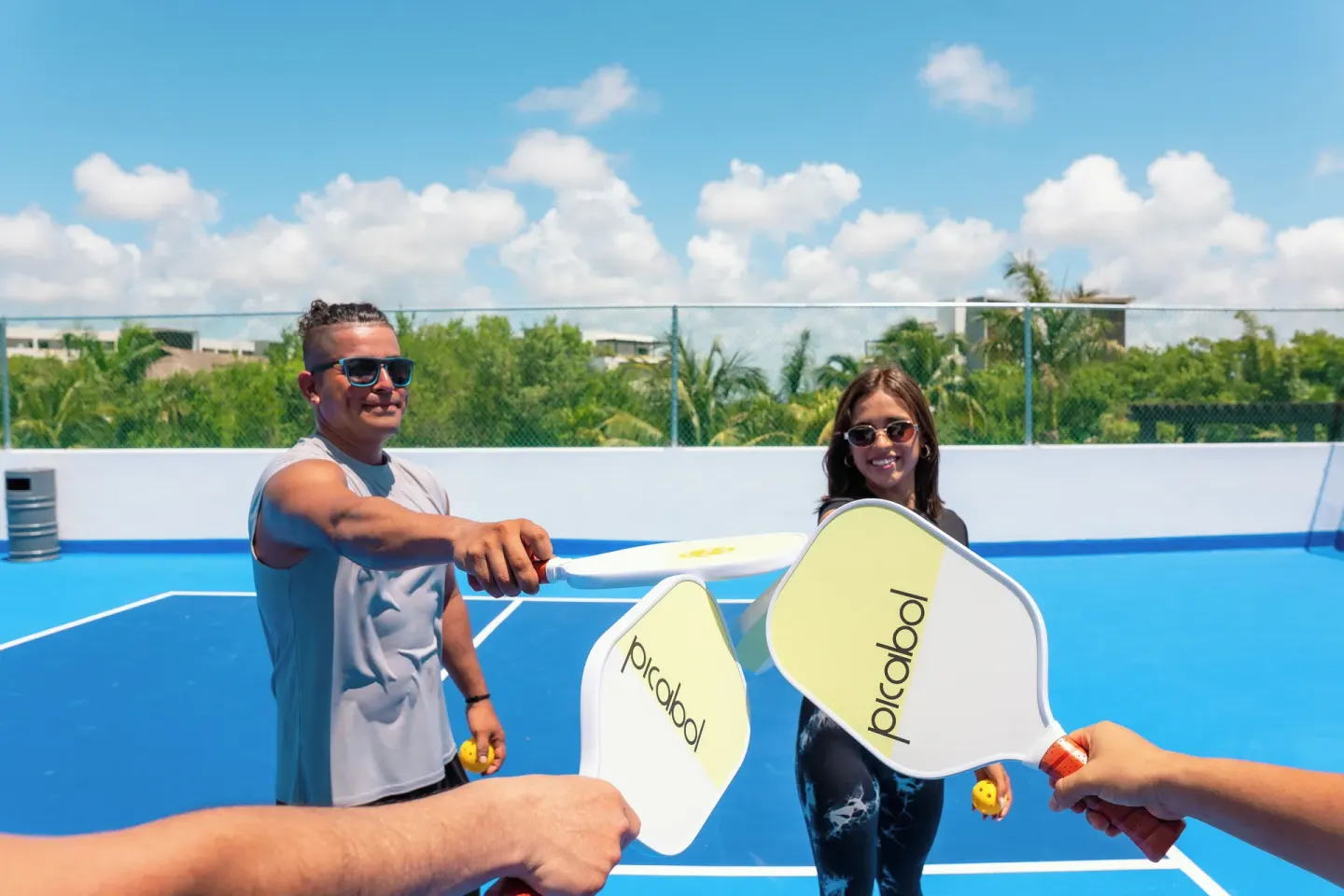 Guests holding pickleball paddles on a blue court at Ventus at Marina El Cid Spa & Beach Resort.