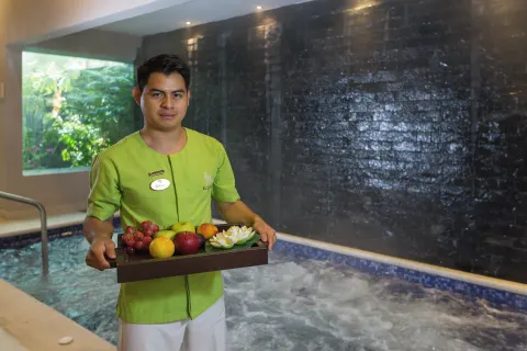 Spa attendant holding a tray of fruit by a pool at Ventus at Marina El Cid Spa & Beach Resort.