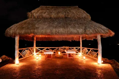 Thatched seaside palapa lit at night at Ventus at Marina El Cid Spa & Beach Resort.