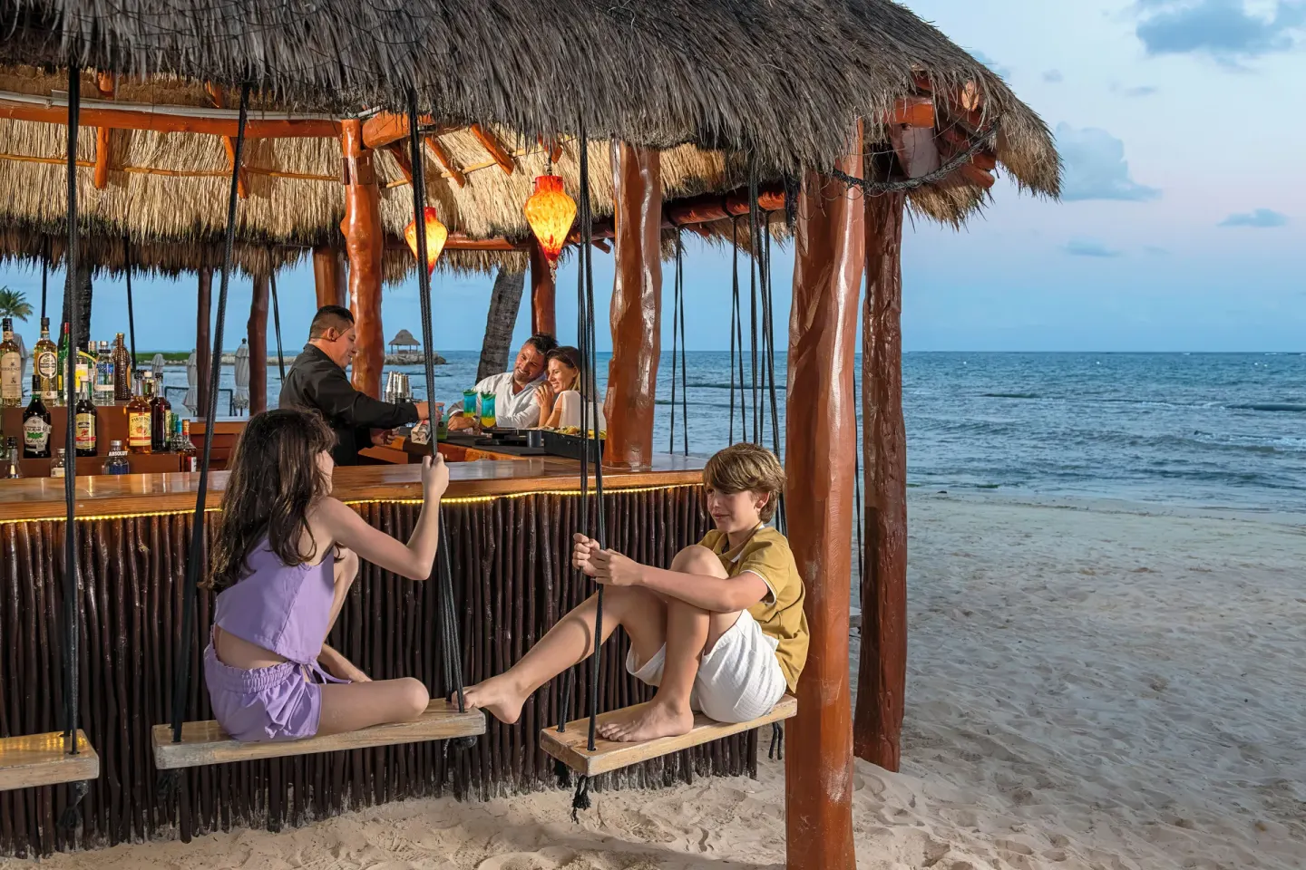 Swing seats at a thatched beach bar by the sea at Ventus at Marina El Cid Spa & Beach Resort.
