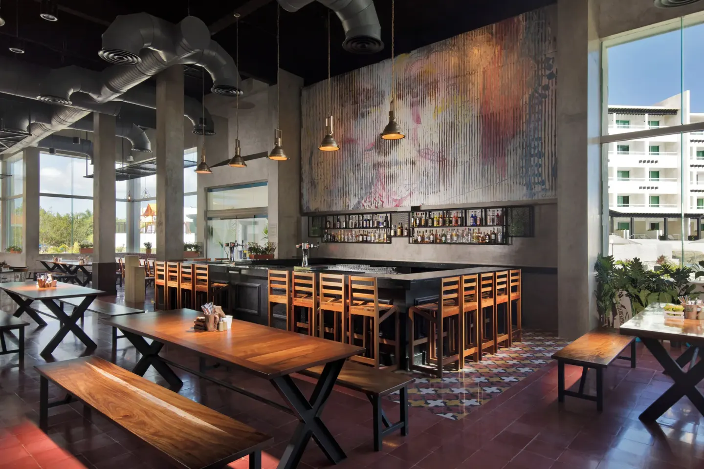 Bar with wood seating and mural wall at Ventus at Marina El Cid Spa & Beach Resort.