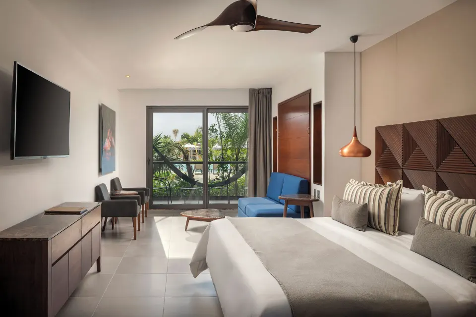 Junior Suite king bed with garden-facing balcony at Ventus at Marina El Cid Spa & Beach Resort.