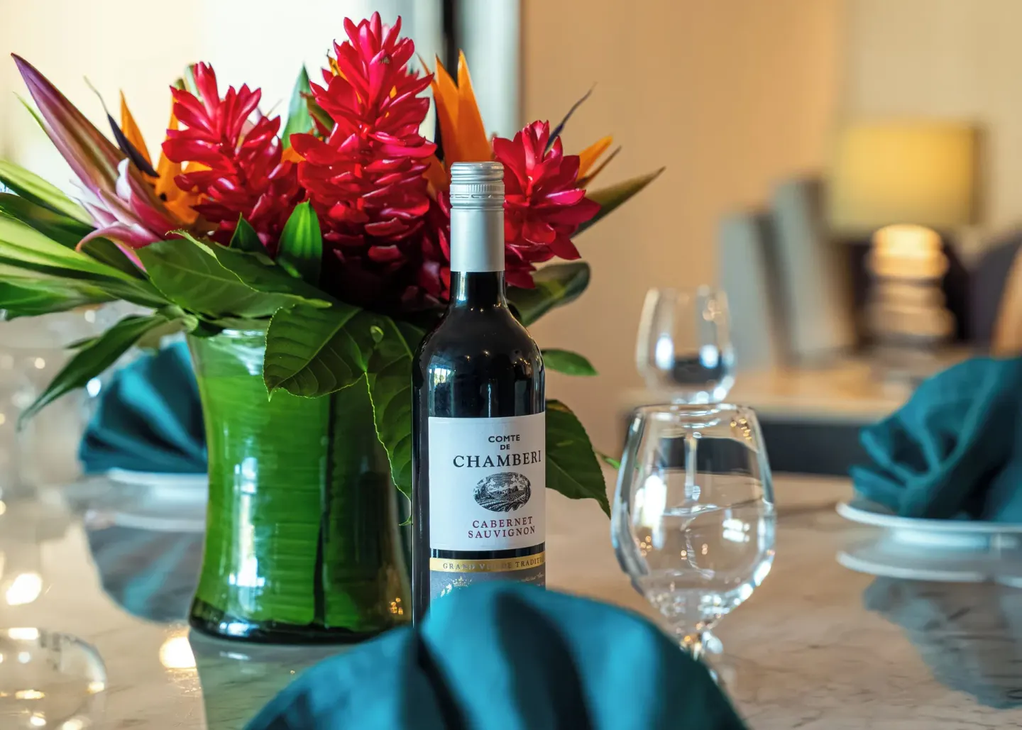 Luxury Platinum room table with wine, glasses, and tropical flowers at Ventus at Marina El Cid Spa & Beach Resort.