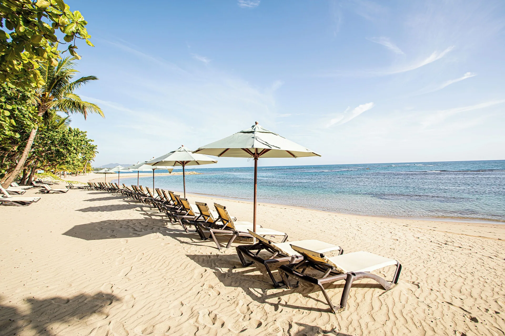 Beach loungers and umbrellas beside calm water at VH Gran Ventana Beach Resort.
