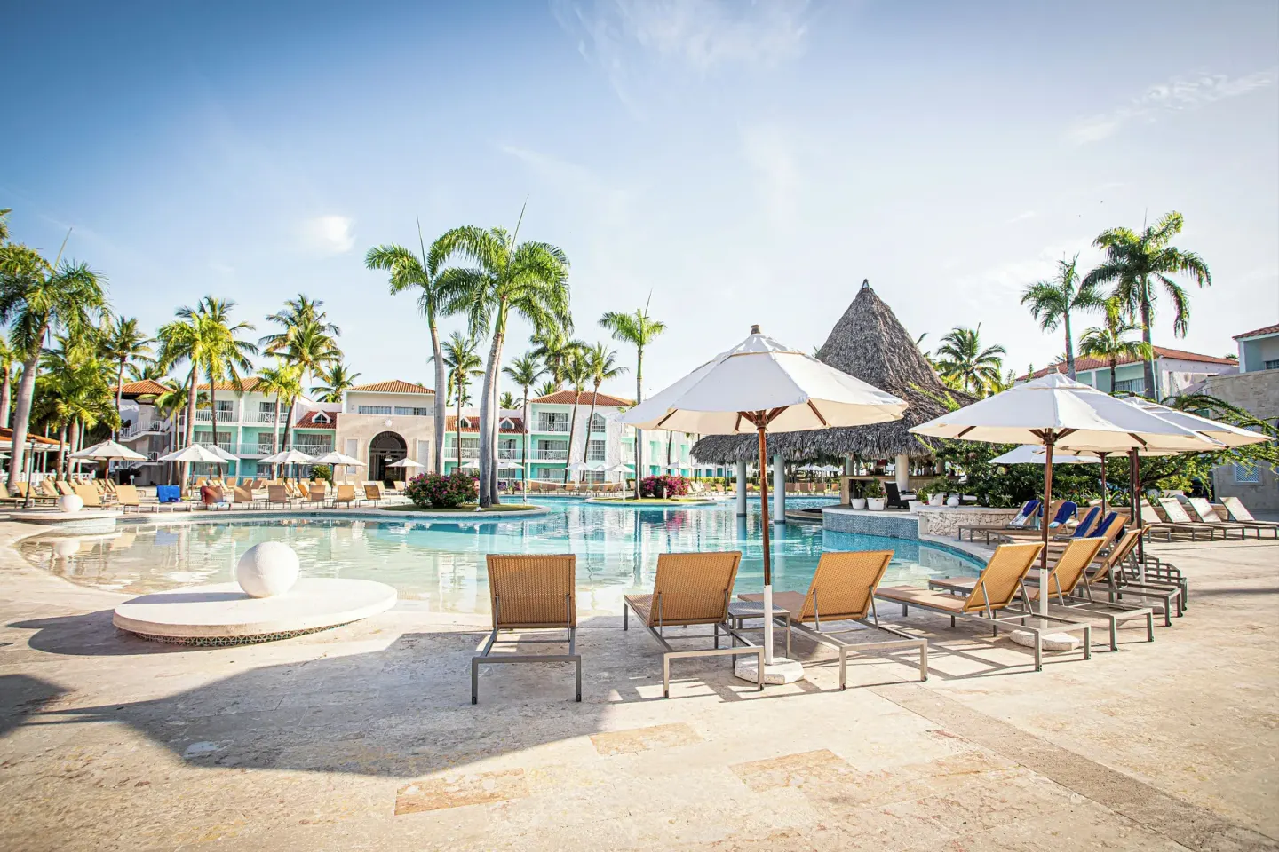 Large resort pool with umbrellas, loungers and a thatched pavilion at VH Gran Ventana Beach Resort.
