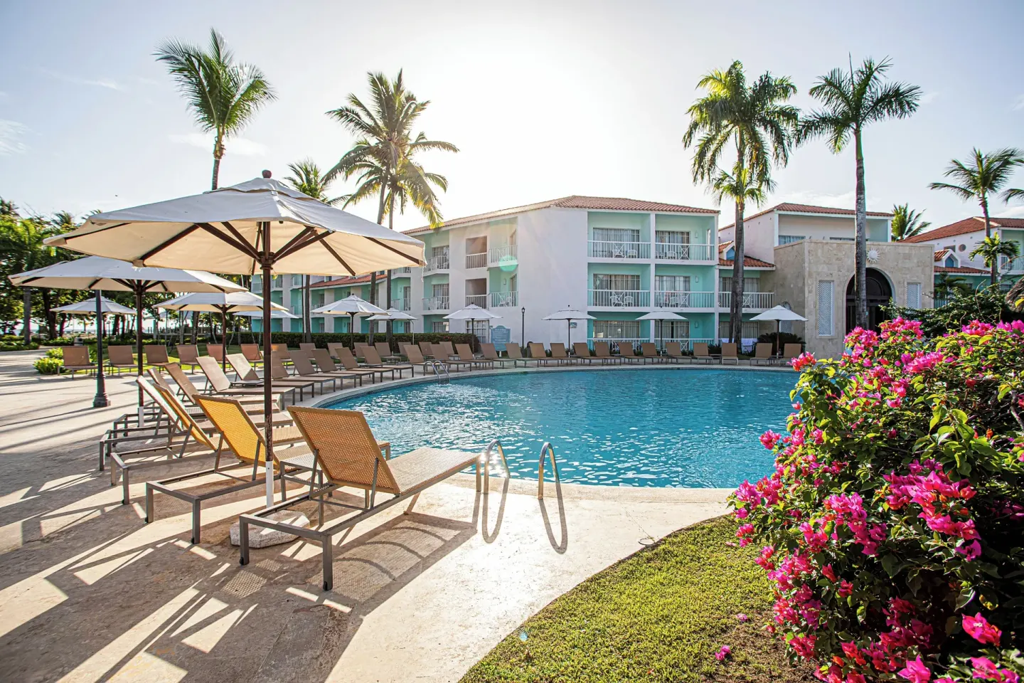 Pool terrace with loungers, umbrellas and flowering shrubs at VH Gran Ventana Beach Resort.