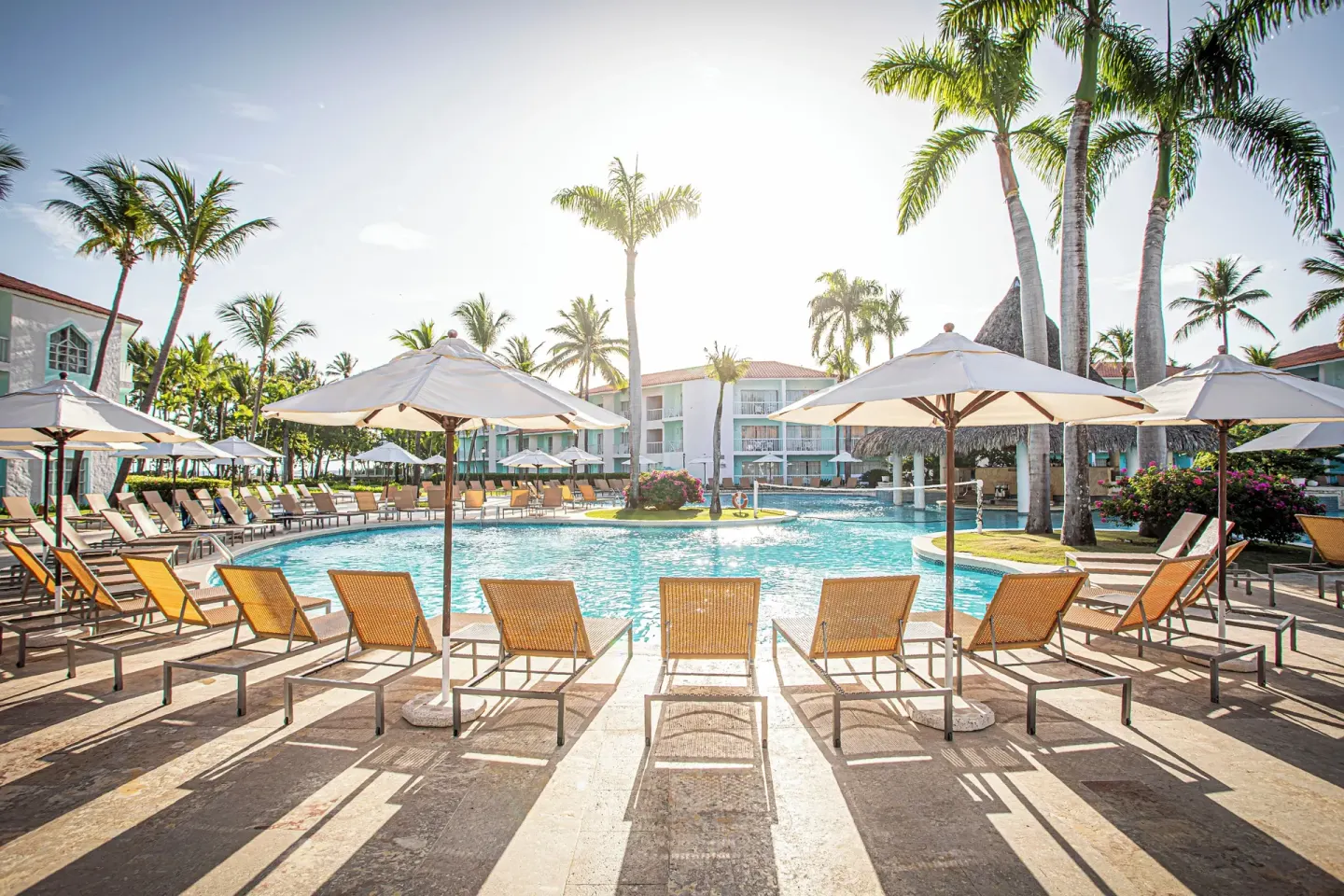 Sunlit resort pool with loungers, umbrellas and palm trees at VH Gran Ventana Beach Resort.
