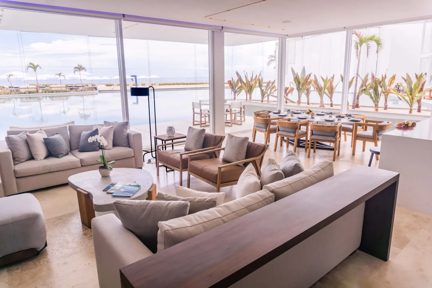 Glass-walled living and dining room overlooking water at Viceroy Los Cabos.
