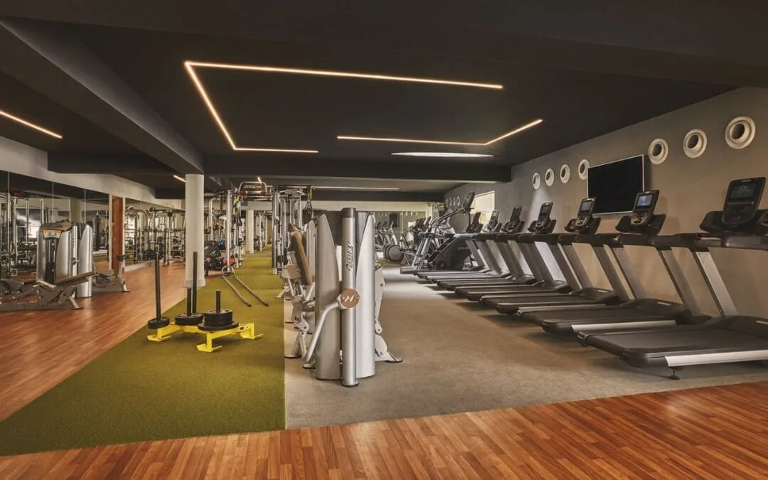 Rows of treadmills, weight machines, turf, and mirrored walls in the gym at Viceroy Los Cabos.