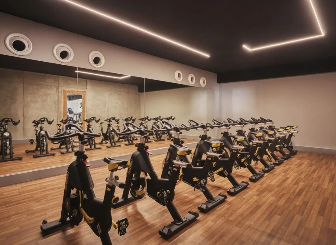 Indoor cycling studio with rows of stationary bikes and a mirrored wall at Viceroy Los Cabos.