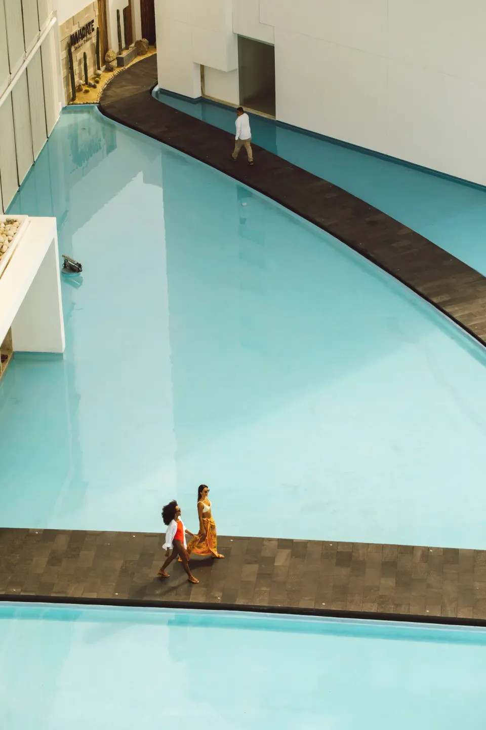 Guests walk along black paths through turquoise pools at Viceroy Los Cabos.