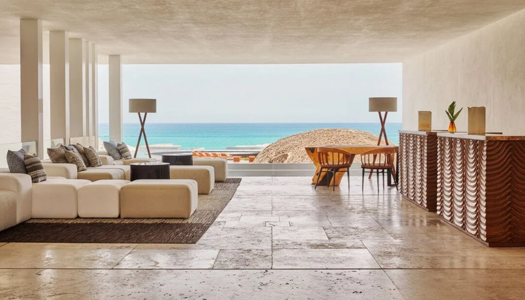 Open-air lounge with sofas, a carved bar, and ocean view at Viceroy Los Cabos.