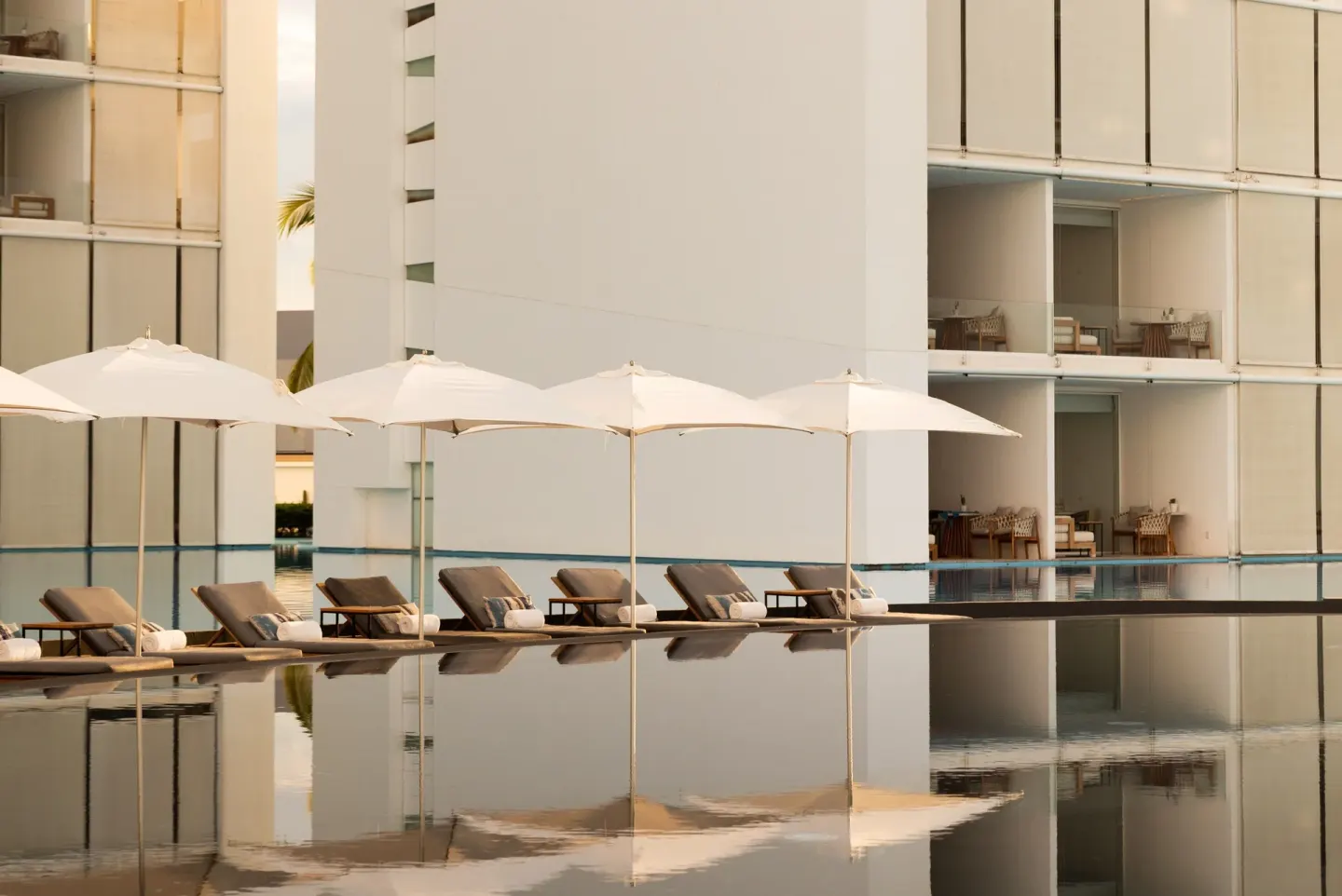 Poolside loungers and white umbrellas beside guest buildings at Viceroy Los Cabos.