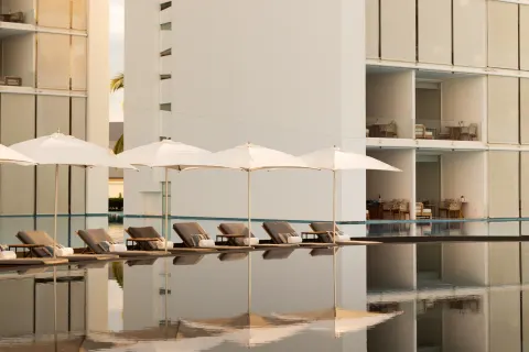 Poolside loungers and white umbrellas beside guest buildings at Viceroy Los Cabos.