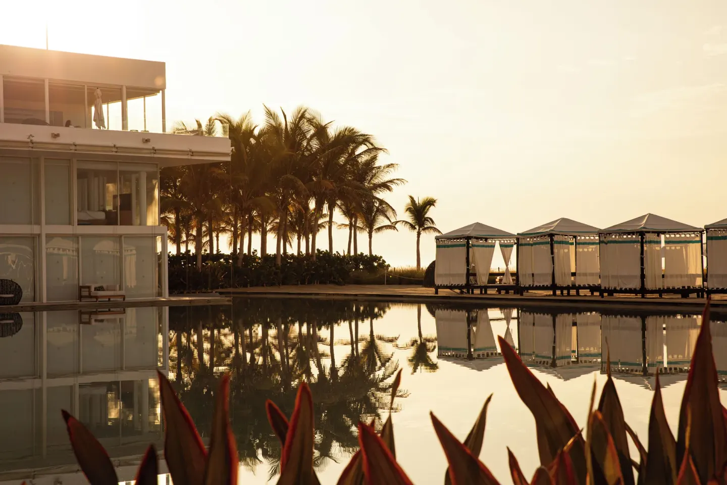 Reflecting pool, cabanas, palms, and resort building at sunset at Viceroy Los Cabos.