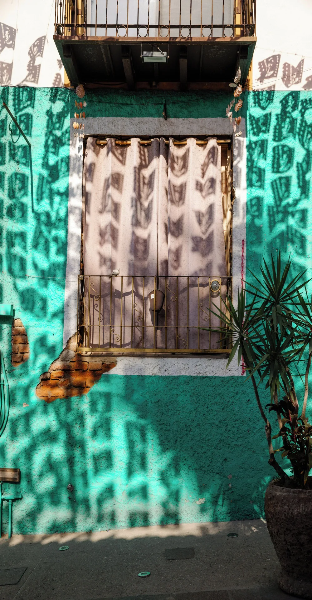 Turquoise stucco wall with balcony and papel picado shadows near Viceroy Los Cabos.