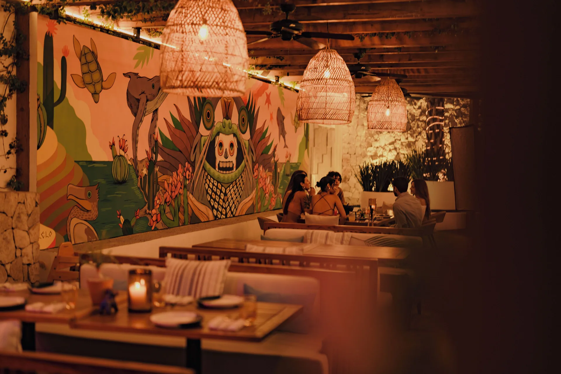 Warm restaurant patio with colorful mural and woven pendant lights at Viceroy Los Cabos.