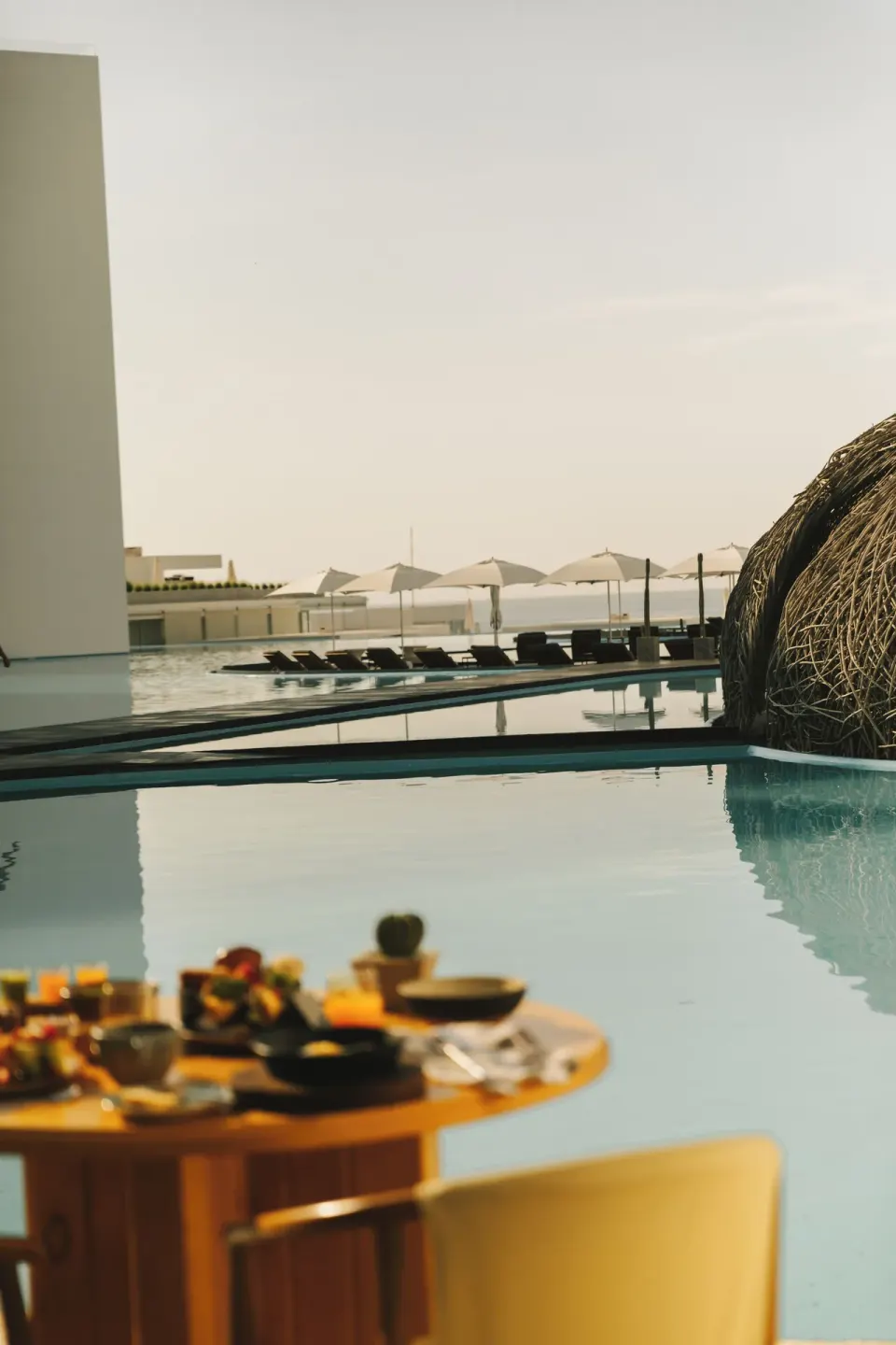 Poolside dining beside the water and woven structure at Viceroy Los Cabos.