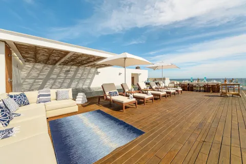 Penthouse terrace lounge with daybed, umbrellas, and dining setup at Viceroy Los Cabos.