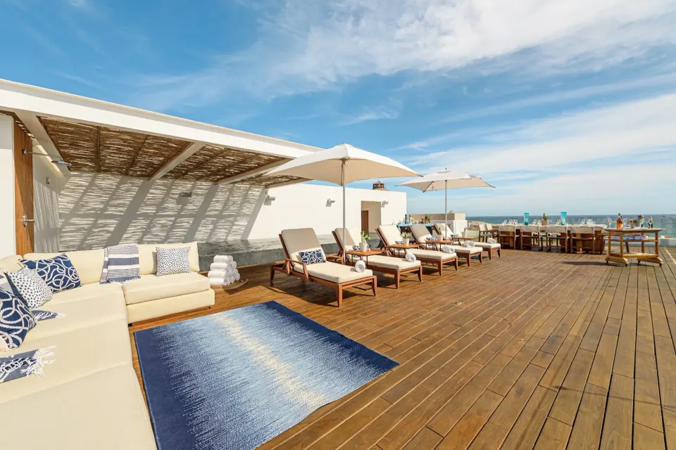 Penthouse terrace lounge with daybed, umbrellas, and dining setup at Viceroy Los Cabos.