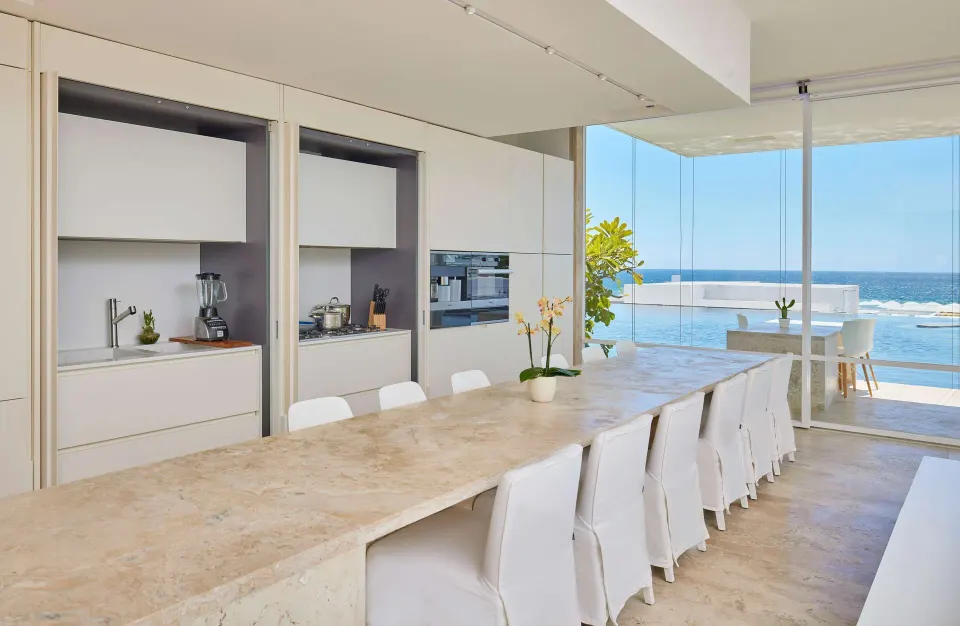 Dining table and kitchen in a 3 Bedroom Waterside Casita at Viceroy Los Cabos with ocean visible beyond.