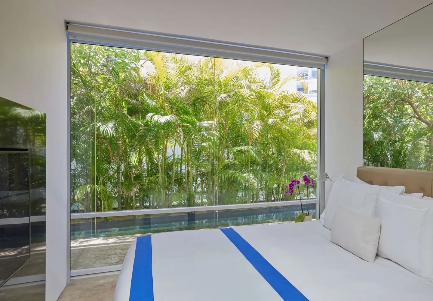 Bedroom in a 3 Bedroom Waterside Casita at Viceroy Los Cabos with garden-framed floor-to-ceiling windows.