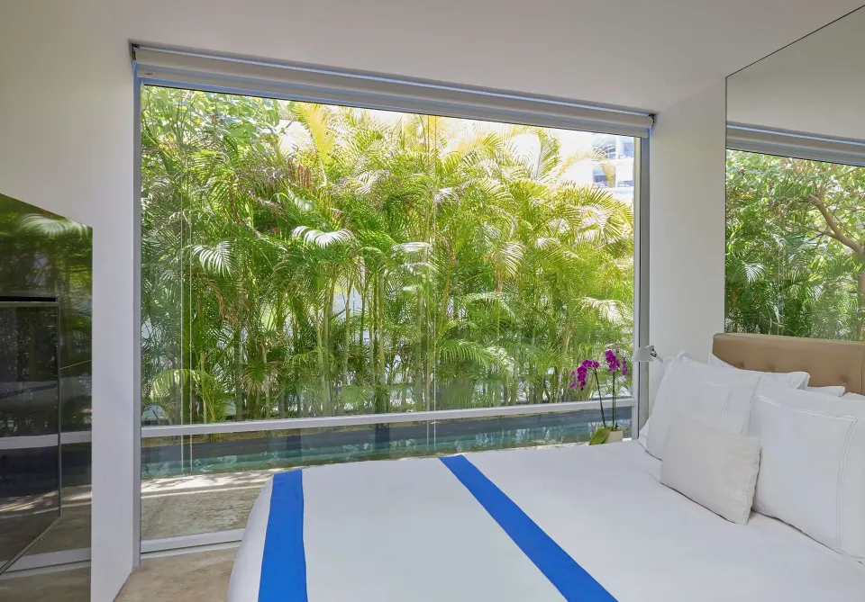 Bedroom in a 3 Bedroom Waterside Casita at Viceroy Los Cabos with garden-framed floor-to-ceiling windows.