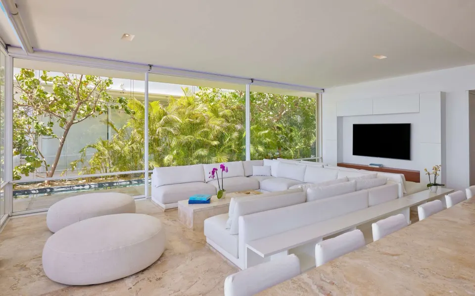 Living and dining area in a 3 Bedroom Waterside Casita at Viceroy Los Cabos with glass walls and greenery.