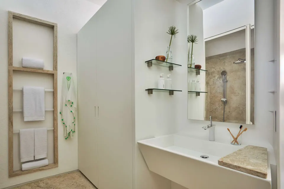 Ocean View room bathroom vanity at Viceroy Los Cabos with mirror, sink, towels, and shower.