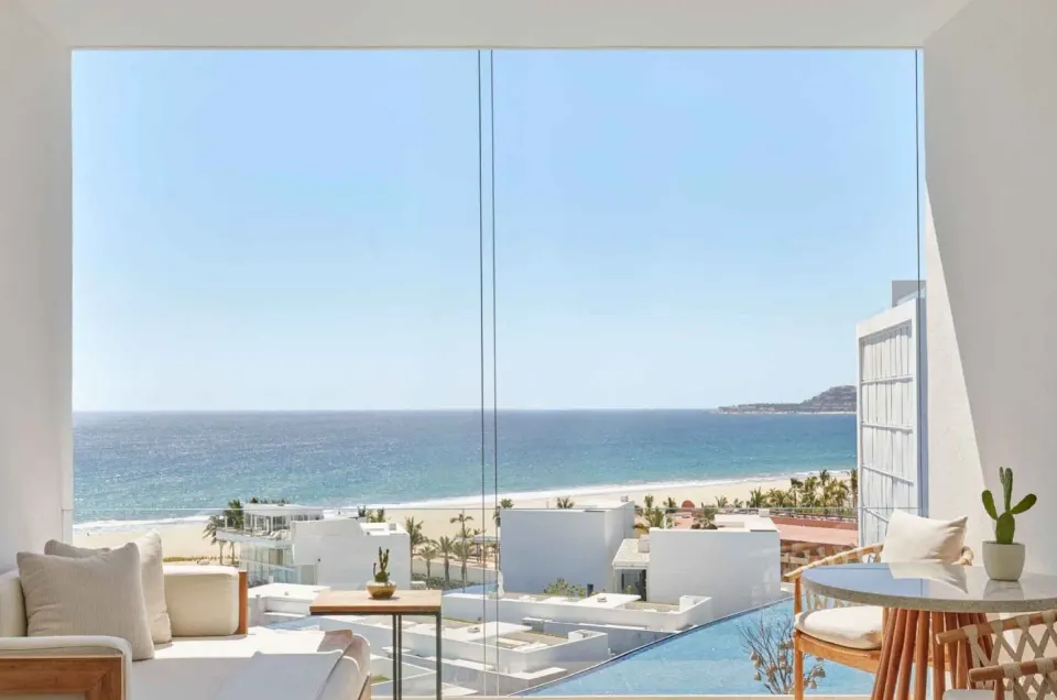 Ocean View room terrace seating at Viceroy Los Cabos with beach and sea visible through glass.