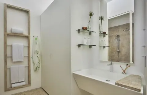 Partial Ocean View room bathroom sink with towel shelves and shower mirror at Viceroy Los Cabos.