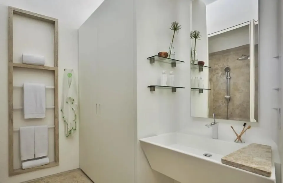Partial Ocean View room bathroom sink with towel shelves and shower mirror at Viceroy Los Cabos.