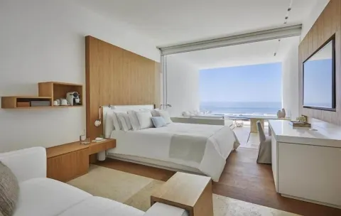 King bed, seating area, TV, and ocean view in a Partial Ocean View room at Viceroy Los Cabos.