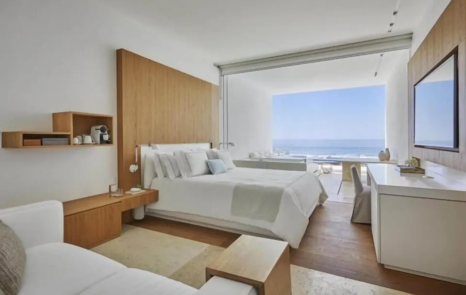 King bed, seating area, TV, and ocean view in a Partial Ocean View room at Viceroy Los Cabos.