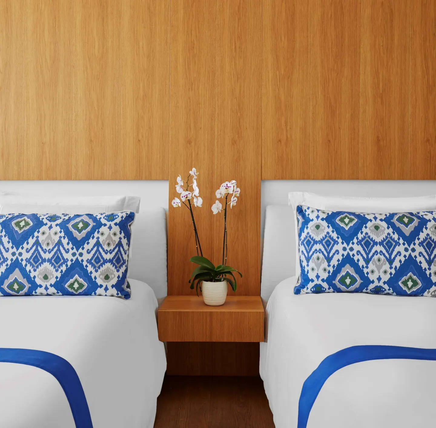 Two white beds with blue patterned pillows in a Partial Ocean View room at Viceroy Los Cabos.