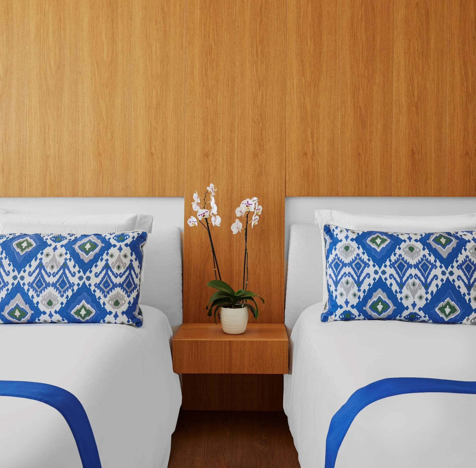 Two white beds with blue patterned pillows in a Partial Ocean View room at Viceroy Los Cabos.